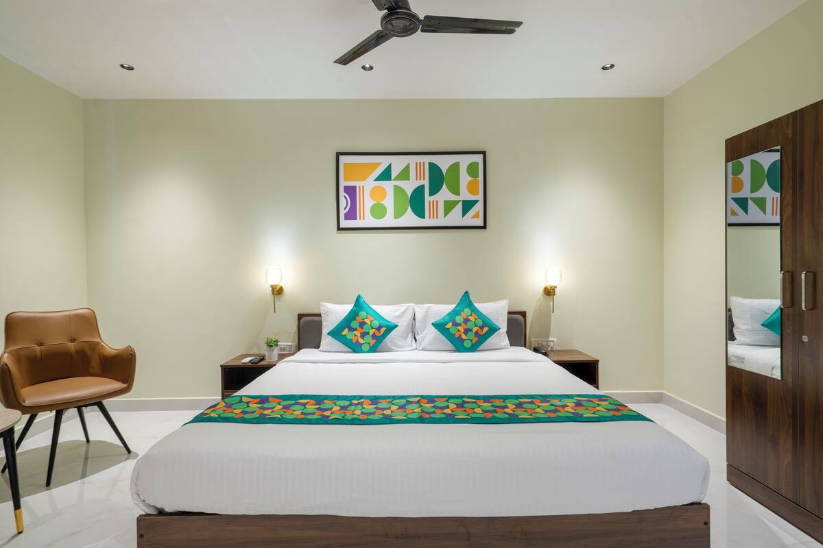 A hotel room with a bed, a chair, a nightstand, a lamp, and a ceiling fan.