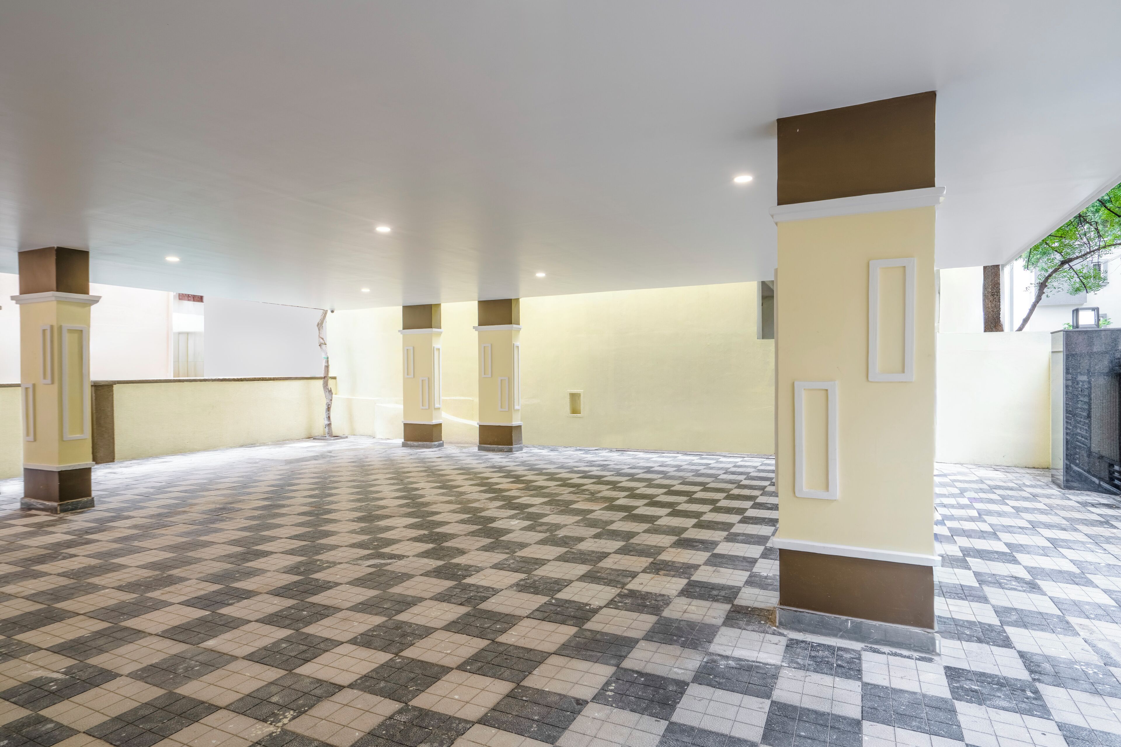 A spacious indoor area with a checkered floor, beige walls, and columns with white frames.