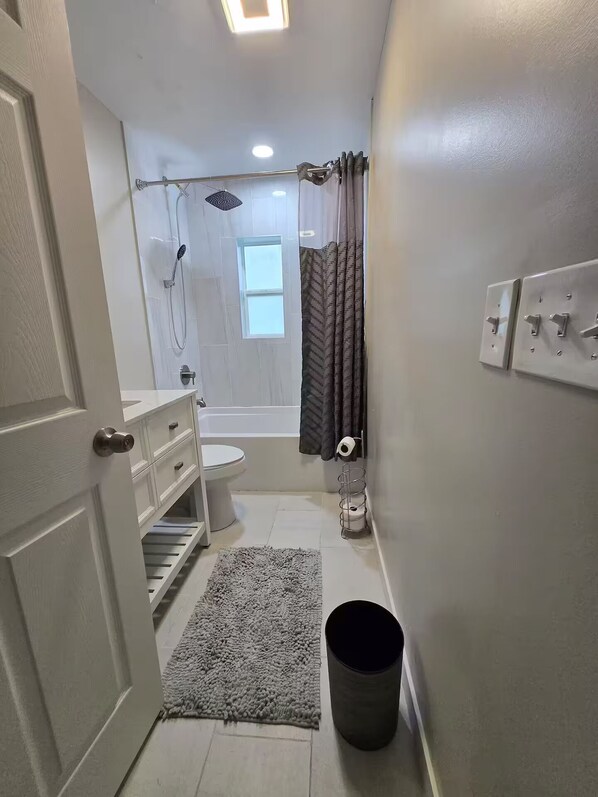 A compact bathroom with a shower, toilet, and sink.