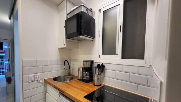 A compact kitchen with a stainless steel sink, a coffee maker, and a built-in oven. - Seaside Apartment Las Palmas Near Playa Canteras (Las Palmas de Gran Canaria)