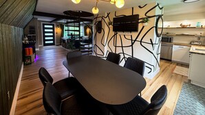 Una cocina moderna con zona de comedor, suelo de madera y lámpara en el techo.