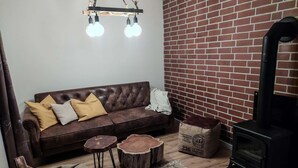 Una sala de estar acogedora con un sofá marrón, una mesa de centro de madera y un estufa de leña negra.