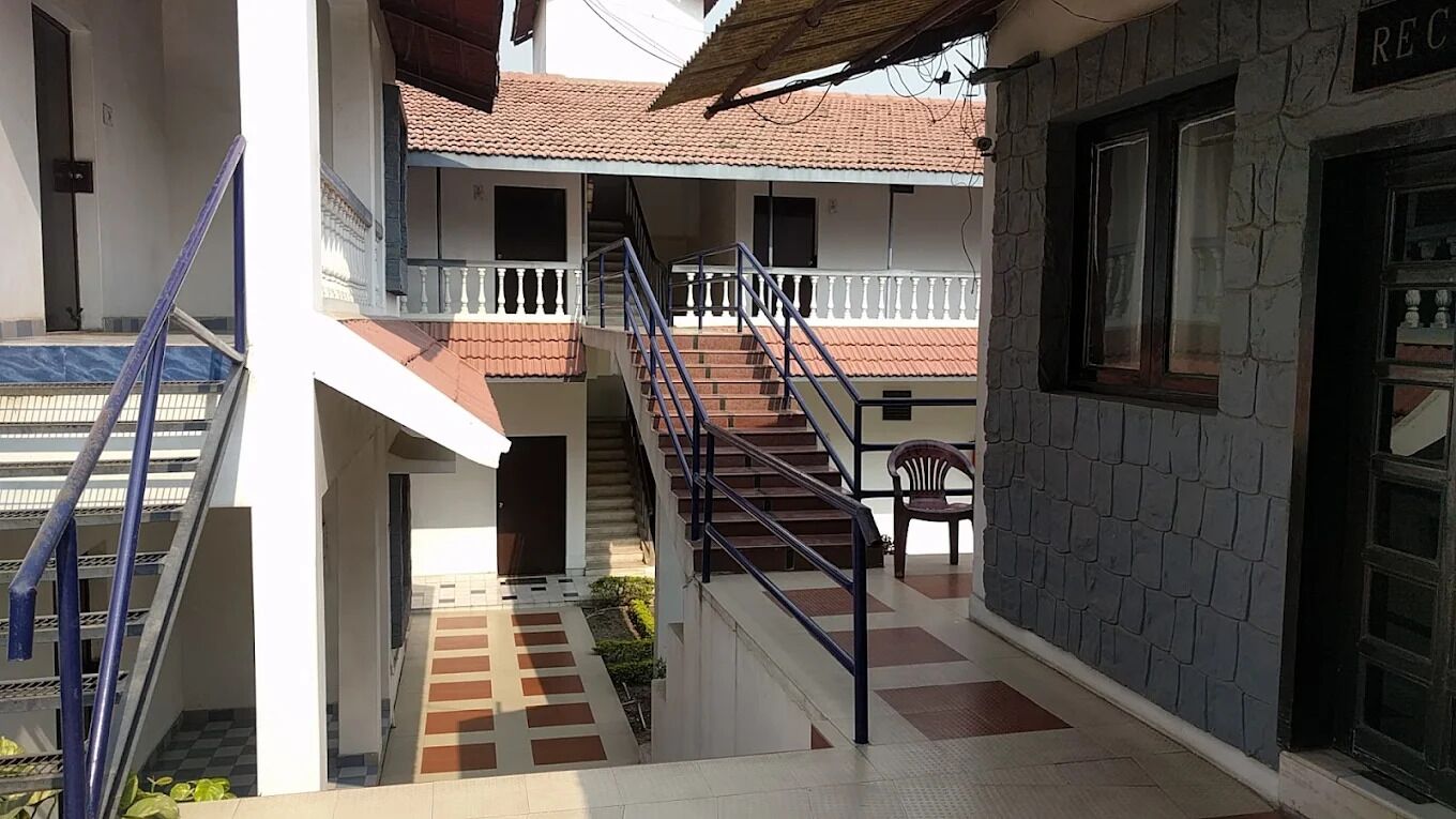 A multi-level building with a staircase, a covered area, and a stone wall.