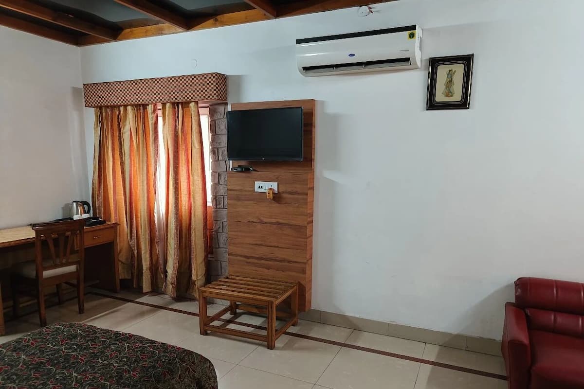 A room with a bed, a desk, a chair, a TV, and an air conditioner.