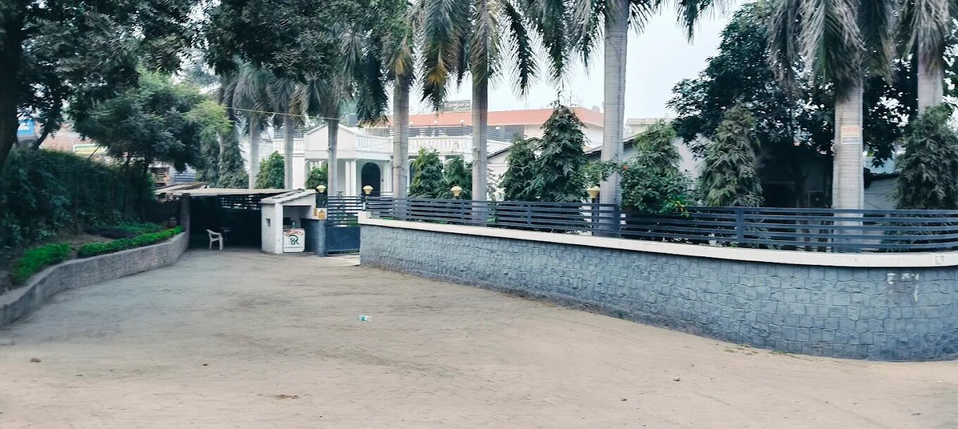 A paved pathway leading to a building with a stone wall and metal railing.