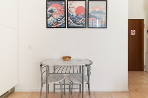 A room with a round table and two chairs, a wooden door, and three framed artworks on the wall. - GuestHost - Cozy Apartment near Piazza Napoli (Milan)