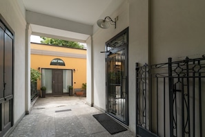 A corridor with a door, a metal gate, and a potted plant.