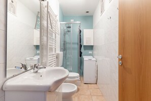 A modern bathroom with a sink, toilet, and shower. - GuestHost - Cozy Apartment near Piazza Napoli (Milan)