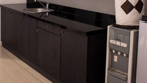Una cocina moderna con encimera negra, pileta integrada y refrigerador. Hay dos cuadros enmarcados en un estante sobre la encimera.