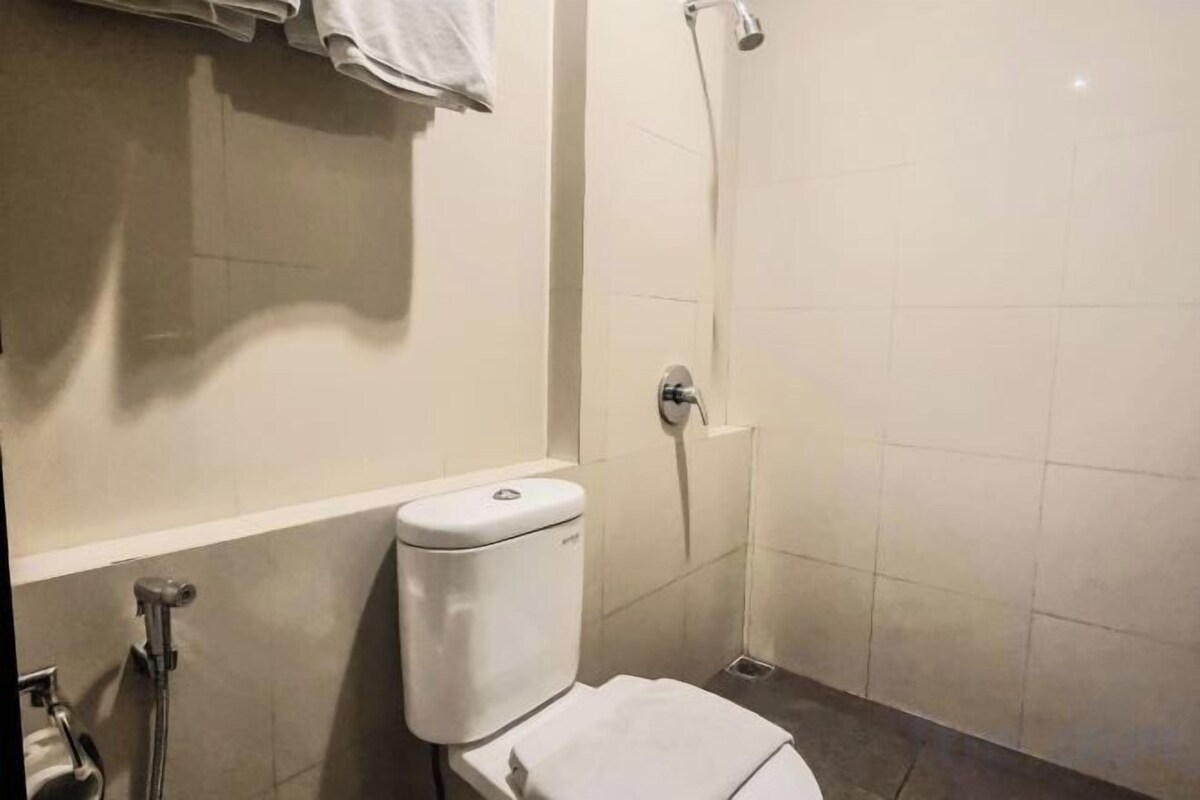 Egy fürdőszoba, amelyben WC, zuhanyzó és törölközőtartó található.