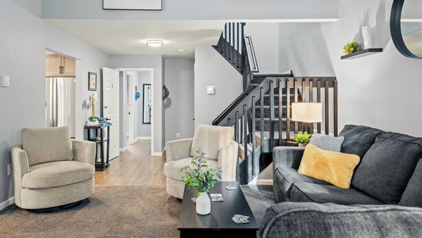 Un salon moderne avec un escalier, des meubles aux couleurs neutres et une décoration minimaliste.