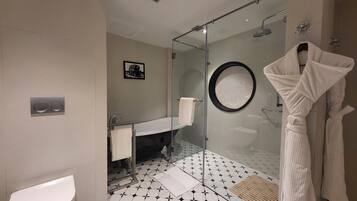 Une salle de bain moderne équipée de toilettes, d’un lavabo et d’une douche à parois de verre.