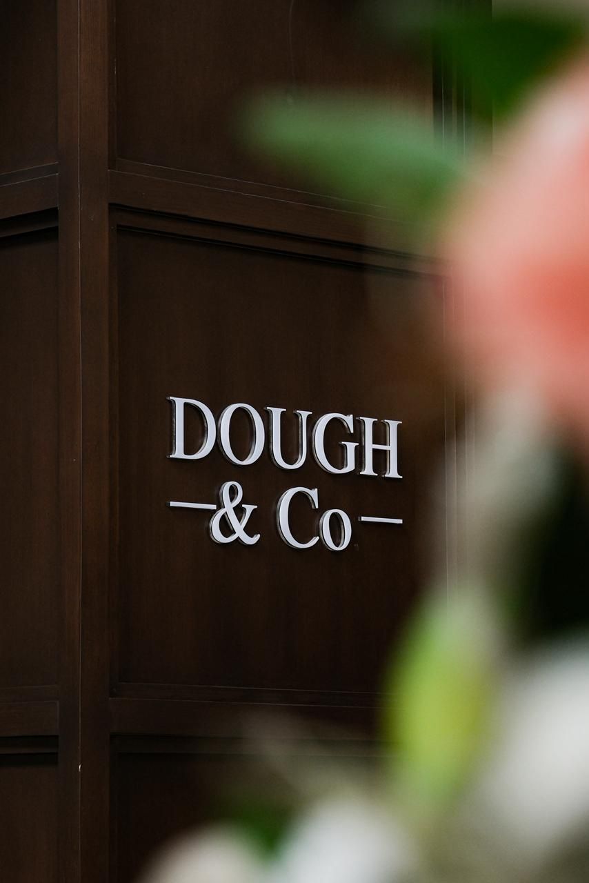 A sign with the text 'DOUGH & Co.' on a wooden door.