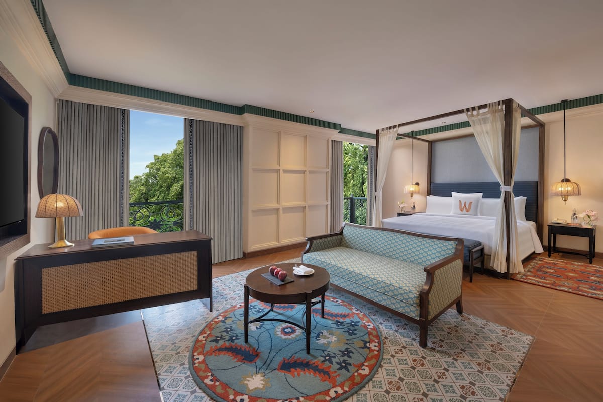 Habitación de hotel con cama, sofá, escritorio y una mesa de centro redonda.