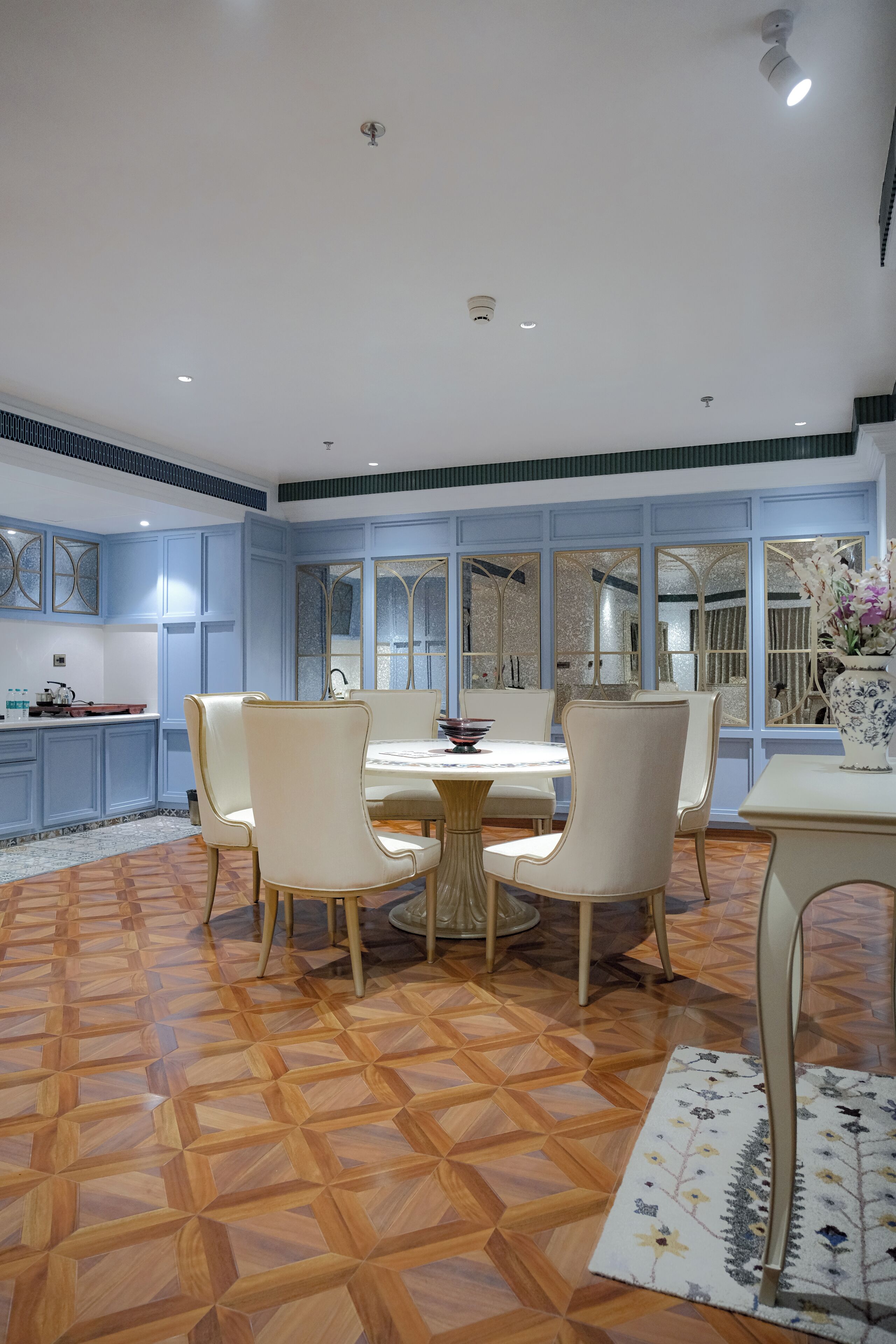 A dining area with a round table, six chairs, and a patterned rug.