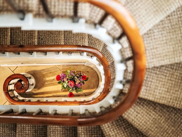 A spiral staircase with a floral arrangement at the bottom.