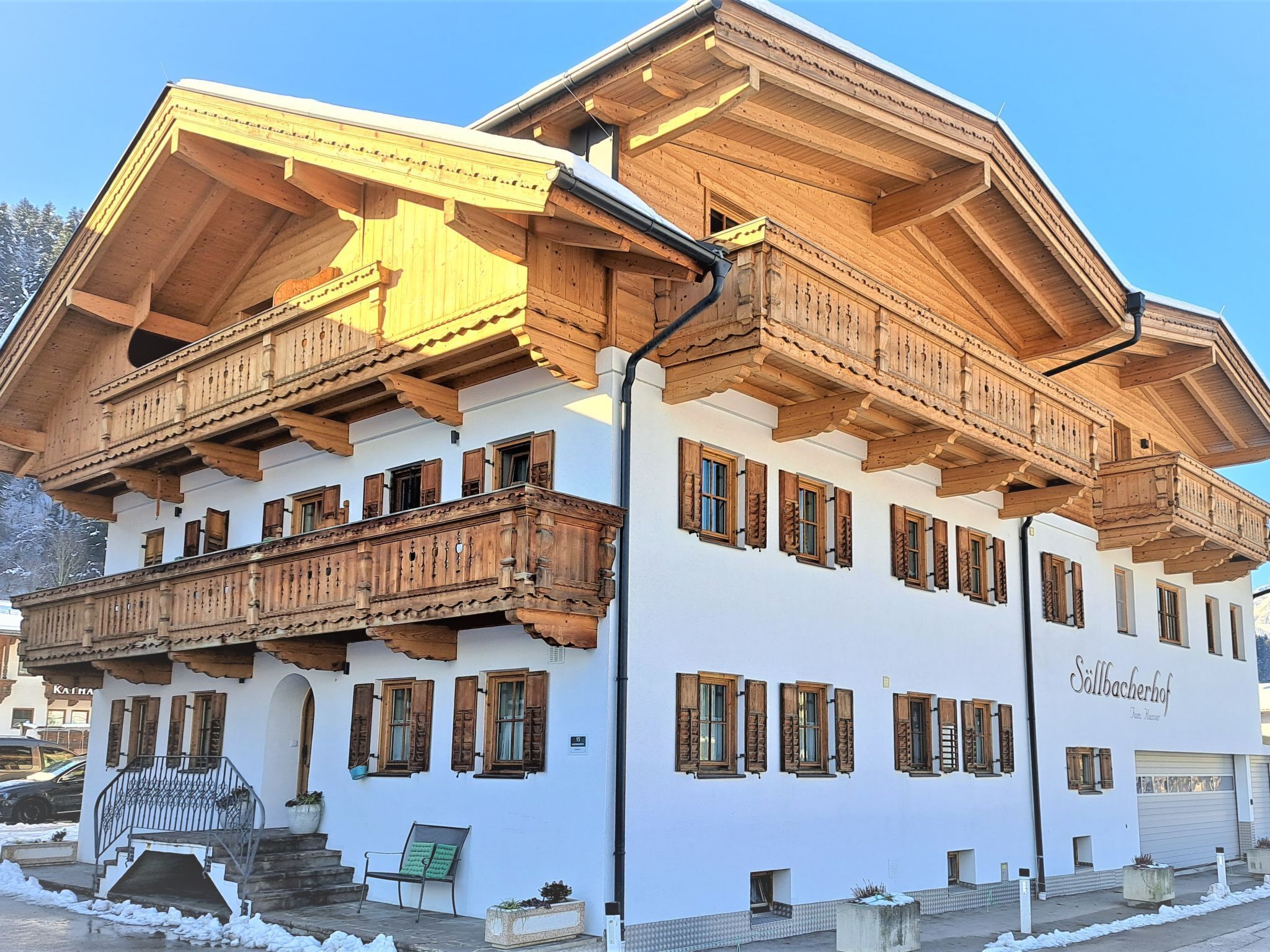 A multi-story building with wooden balconies and a white facade.