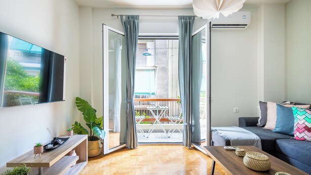 Un salon moderne avec un plancher en bois, un canapé, un téléviseur et un coin repas comprenant une table et des chaises.