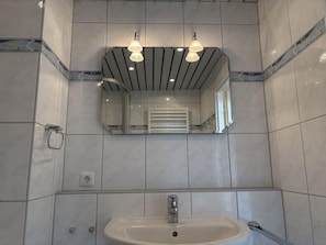 A bathroom with a white sink, a mirror, and two pendant lights.