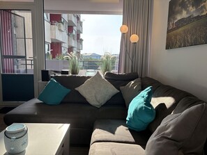En moderne stue med en hjørnesofa, et lille bord og en potteplante.