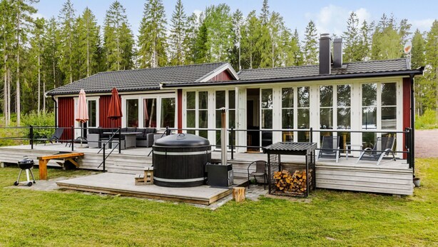 A cabin with a deck, outdoor seating, a grill, and a large water heater. - Jönsamåla by Interhome (Ryd)
