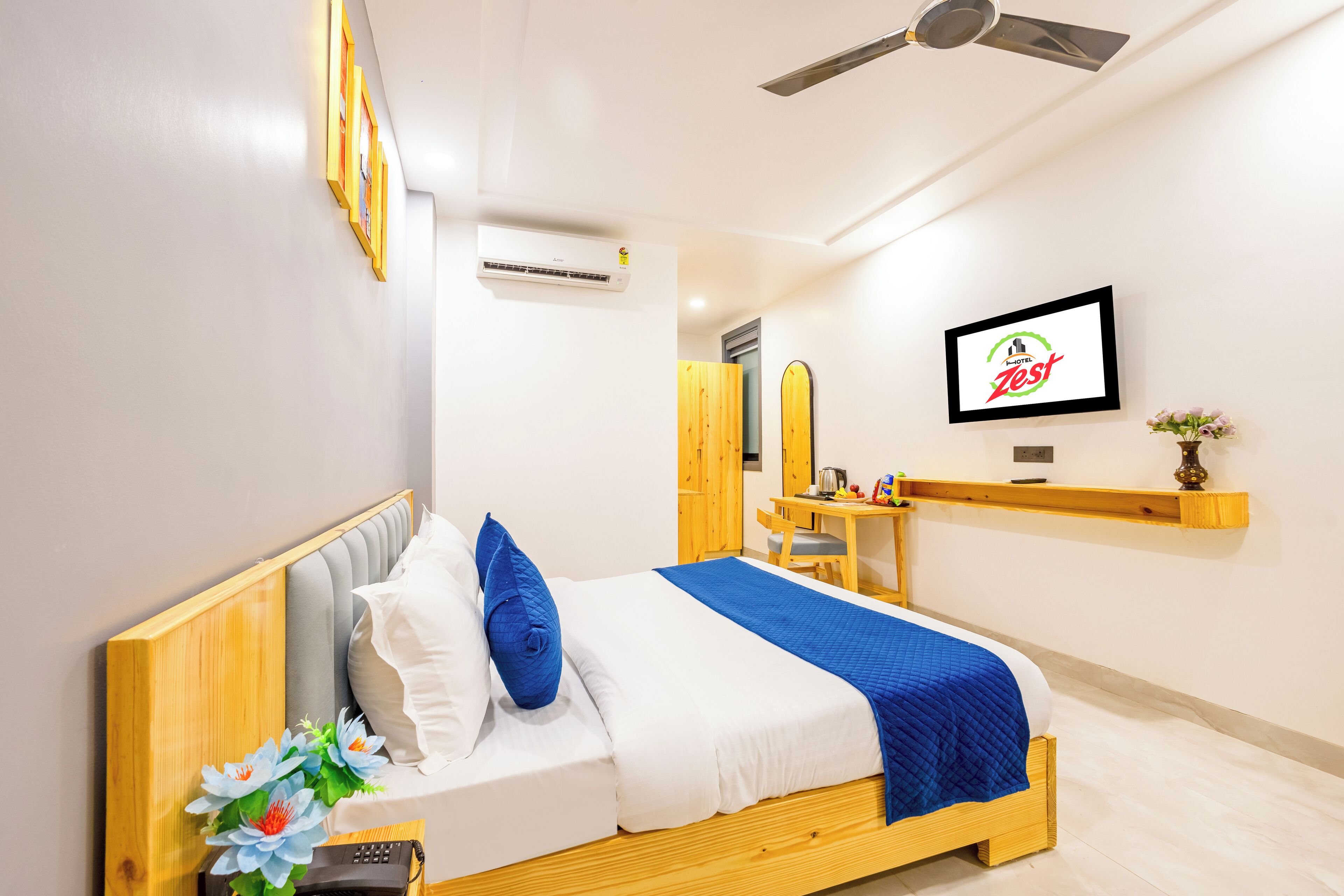 Una camera d'albergo moderna con un letto in legno, una TV a parete e una piccola scrivania con una sedia.