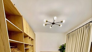 A bedroom with a bed, wooden wardrobe, a ceiling light fixture, and a plant. - 2Bedroom Apartment and Living Room at Shiekh Zayed (First 6th of October)