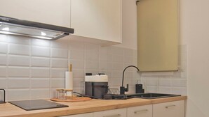 A modern kitchen with white cabinets, a wooden countertop, a built-in oven, and a window above the sink. - Historic Boutique Apartment in Artists' Kipseli (Athina)