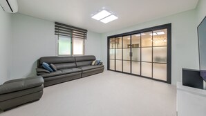 Una sala moderna con un sofá, una mesita y un ventanal corredera que da a una cocina.