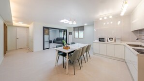 Una cocina moderna con armarios blancos, una mesa de comedor con sillas y un microondas.