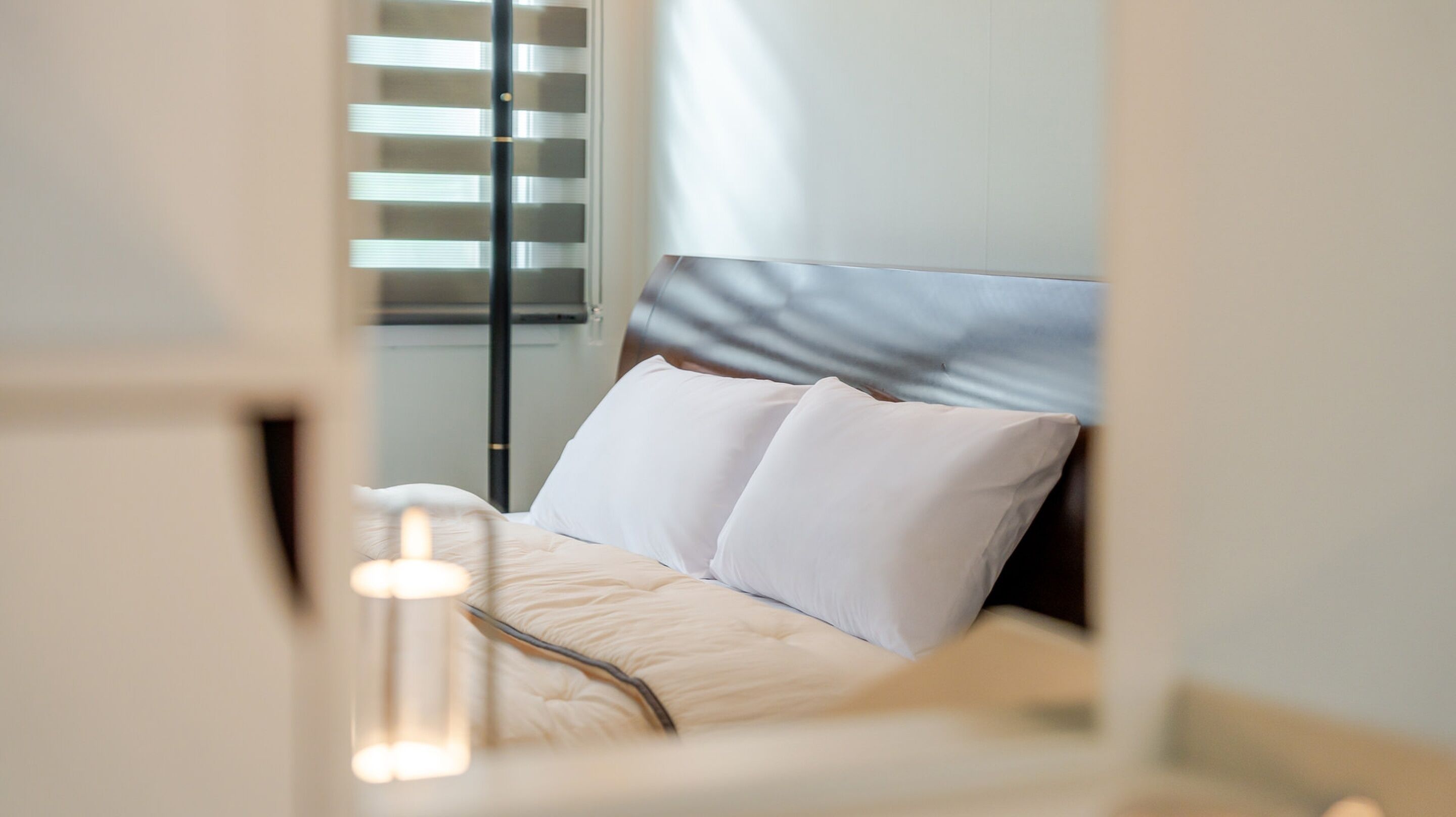 A modern bedroom with a bed, white pillows, and a headboard.