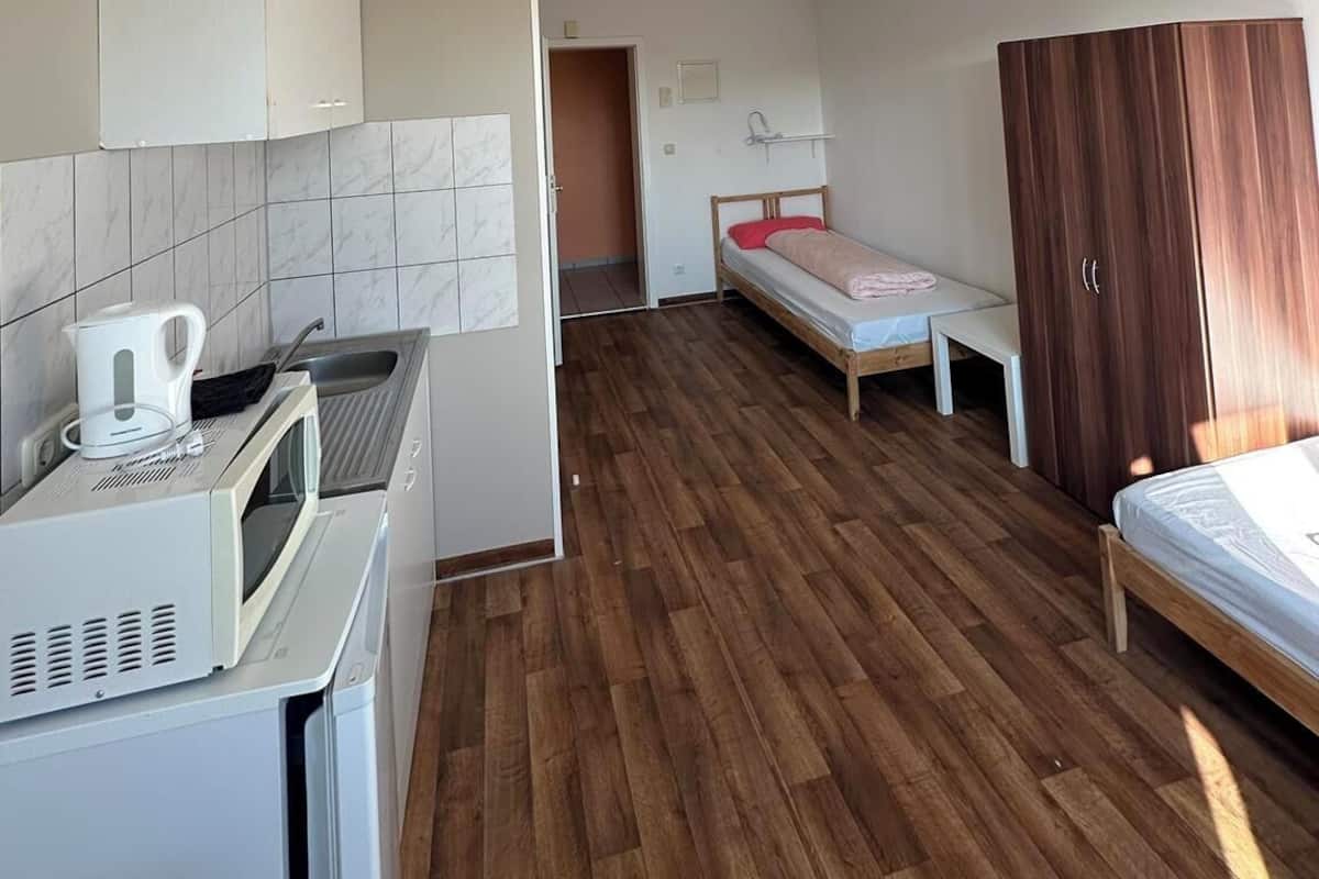 Una habitación pequeña con kitchenette, una cama y un armario.