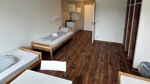 Une chambre compacte avec deux lits simples, une petite kitchenette et une armoire.