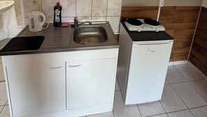 Une petite cuisine équipée d’un évier, d’une bouilloire et d’un réfrigérateur compact.