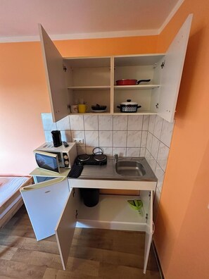 Una cocina compacta con microondas, tostadora y lavabo.
