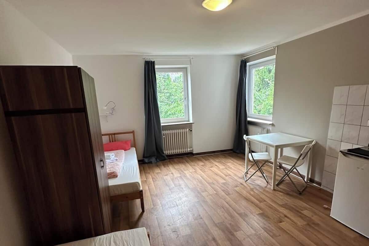 Una habitación pequeña y bien iluminada con una cama, un escritorio y un radiador.