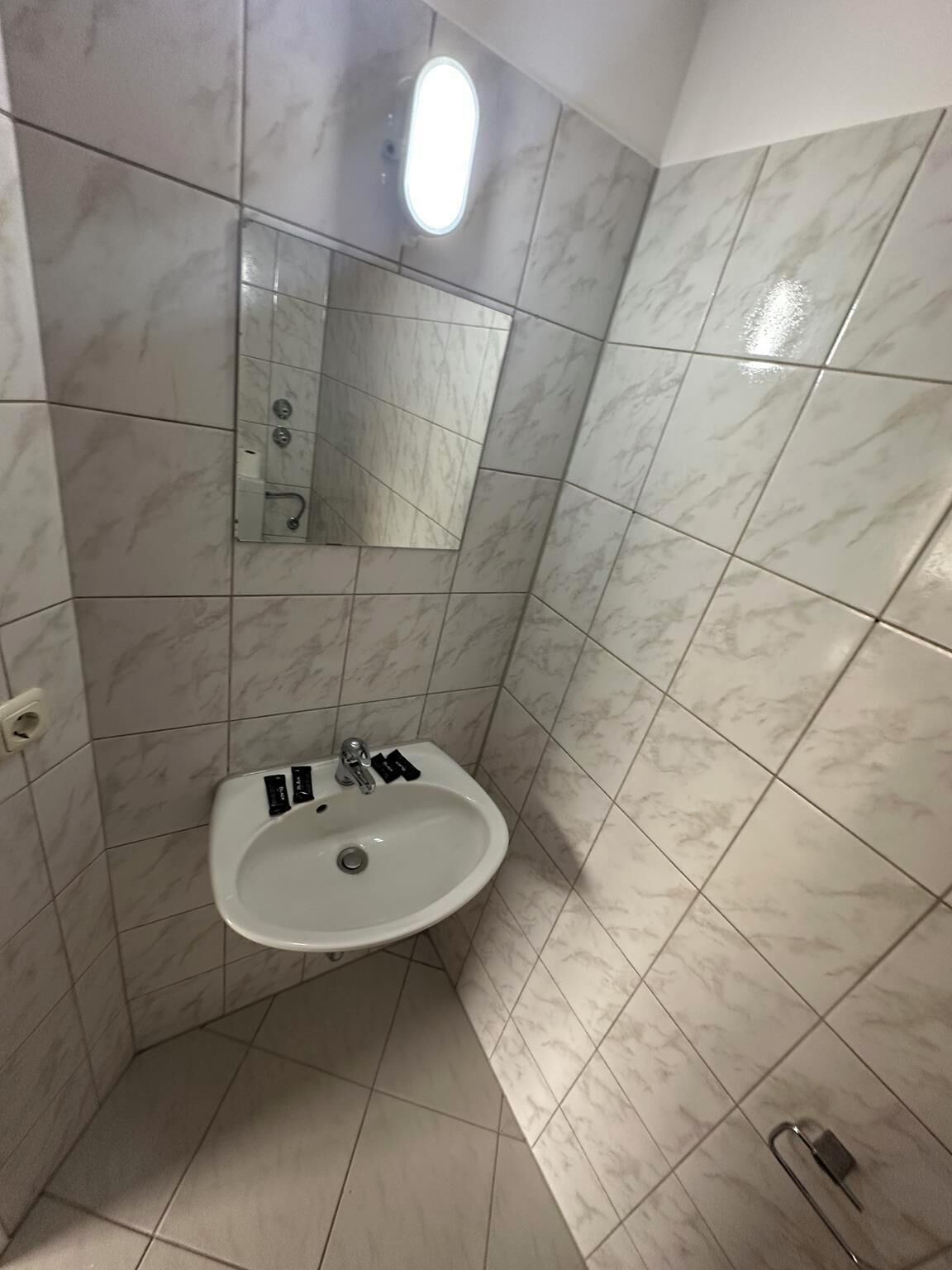 Ein Badezimmer mit Waschbecken, Spiegel und gefliesten Wänden.