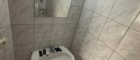 A bathroom with a sink, mirror, and tiled walls.