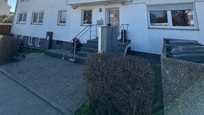 Un immeuble à plusieurs étages doté d’une façade plane, d’un escalier menant à l’entrée et d’un ciel dégagé.