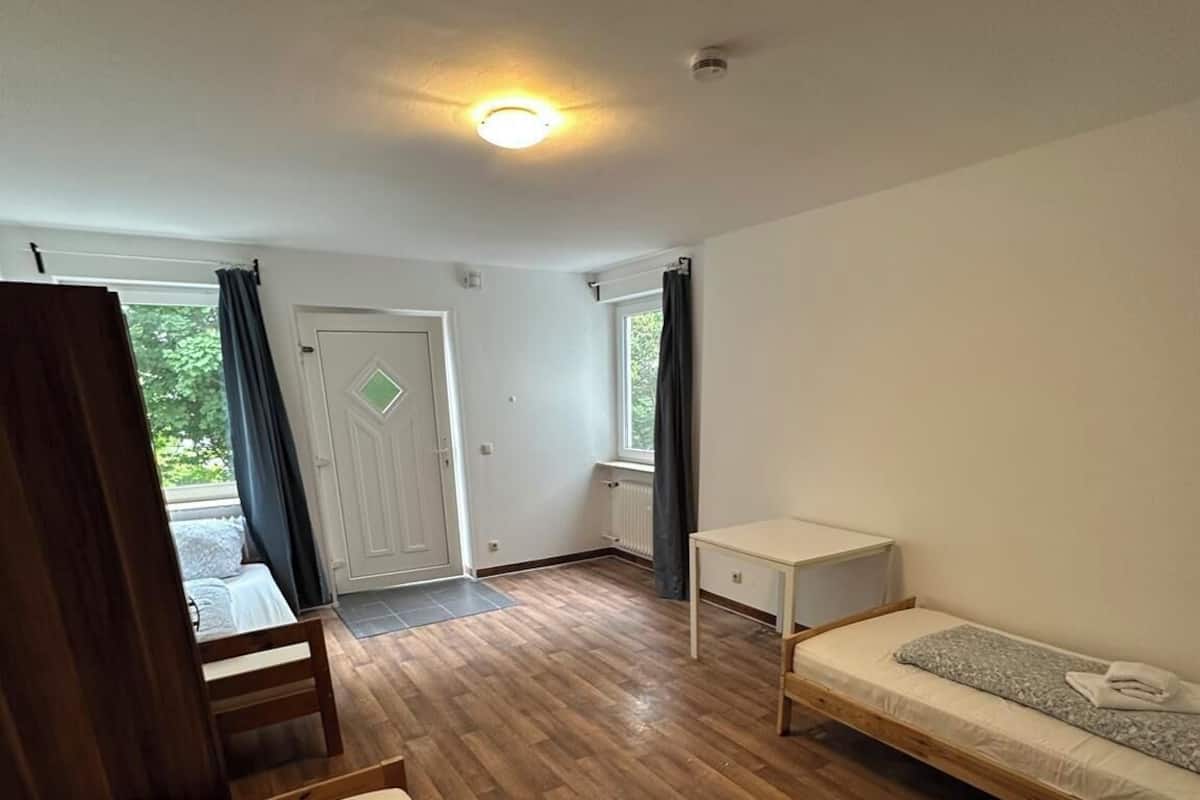 Una habitación con una cama, una mesita, una ventana y una puerta.