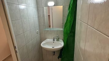 Un baño pequeño con lavamanos, espejo y cortina de ducha verde.