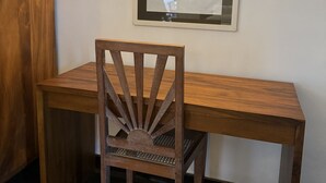 Un bureau en bois avec une chaise, une œuvre d’art encadrée accrochée au mur et un luminaire fixé au mur.