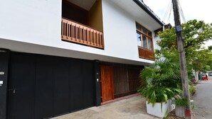 Un immeuble résidentiel de deux étages avec une porte de garage noire, des balustrades de balcon en bois et une façade blanche.