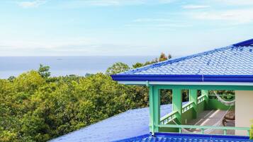 A building with a blue tiled roof and a green structure with stairs leading to a balcony.