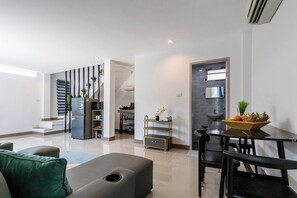 Un salon moderne comprenant un canapé, une table à manger avec des chaises, un escalier et un coin cuisine.