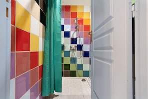 A bathroom with colorful tiles, a shower, and a door.