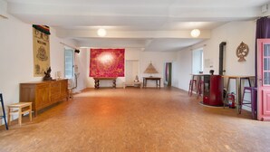 A spacious room with a wooden floor, a wooden cabinet, a red tapestry, and a pink door. - Domaine de La Contie – 17th-Century Chartreuse in the Heart of 20 Hectares of Nature (Issac)