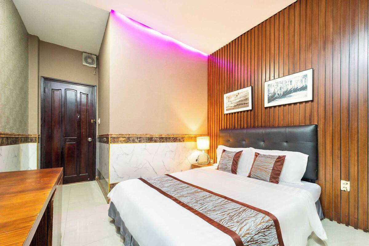 Ein Hotelzimmer mit einem Bett, Holzwandverkleidung, einer Marmor-Akzentwand, einem Schreibtisch und zwei gerahmten Bildern.