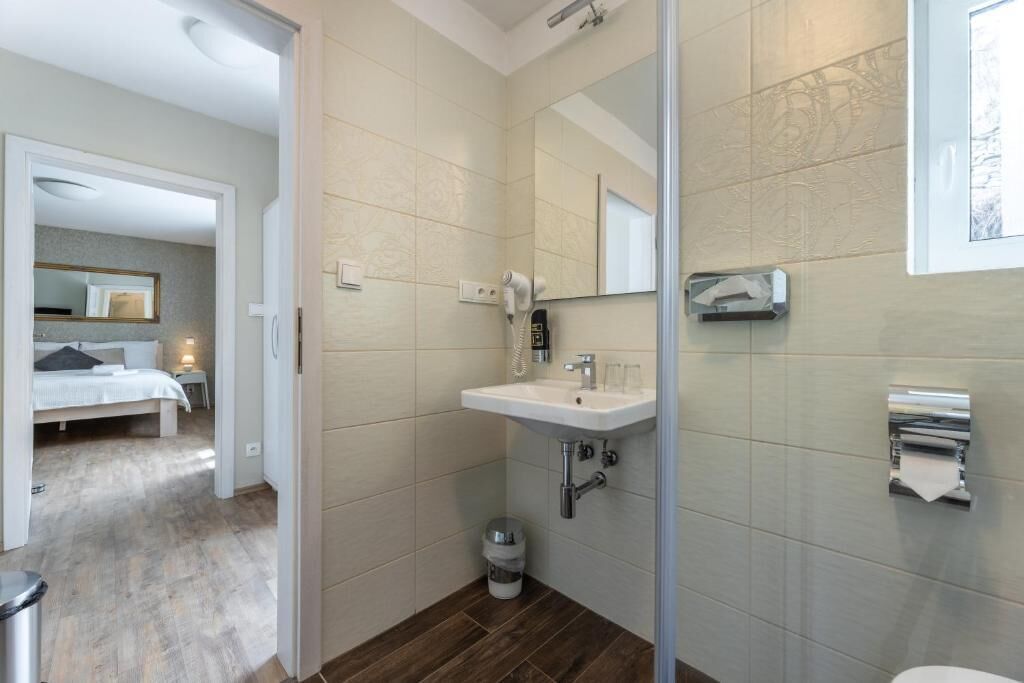 Un baño moderno con lavamanos, espejo y dispensador de toallas.