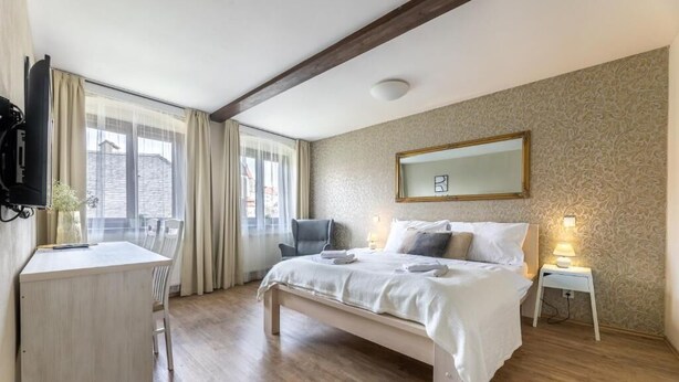A bedroom with a bed, bedside table, chair, desk, and a TV. - Apartmány U Pavla (Cesky Krumlov)